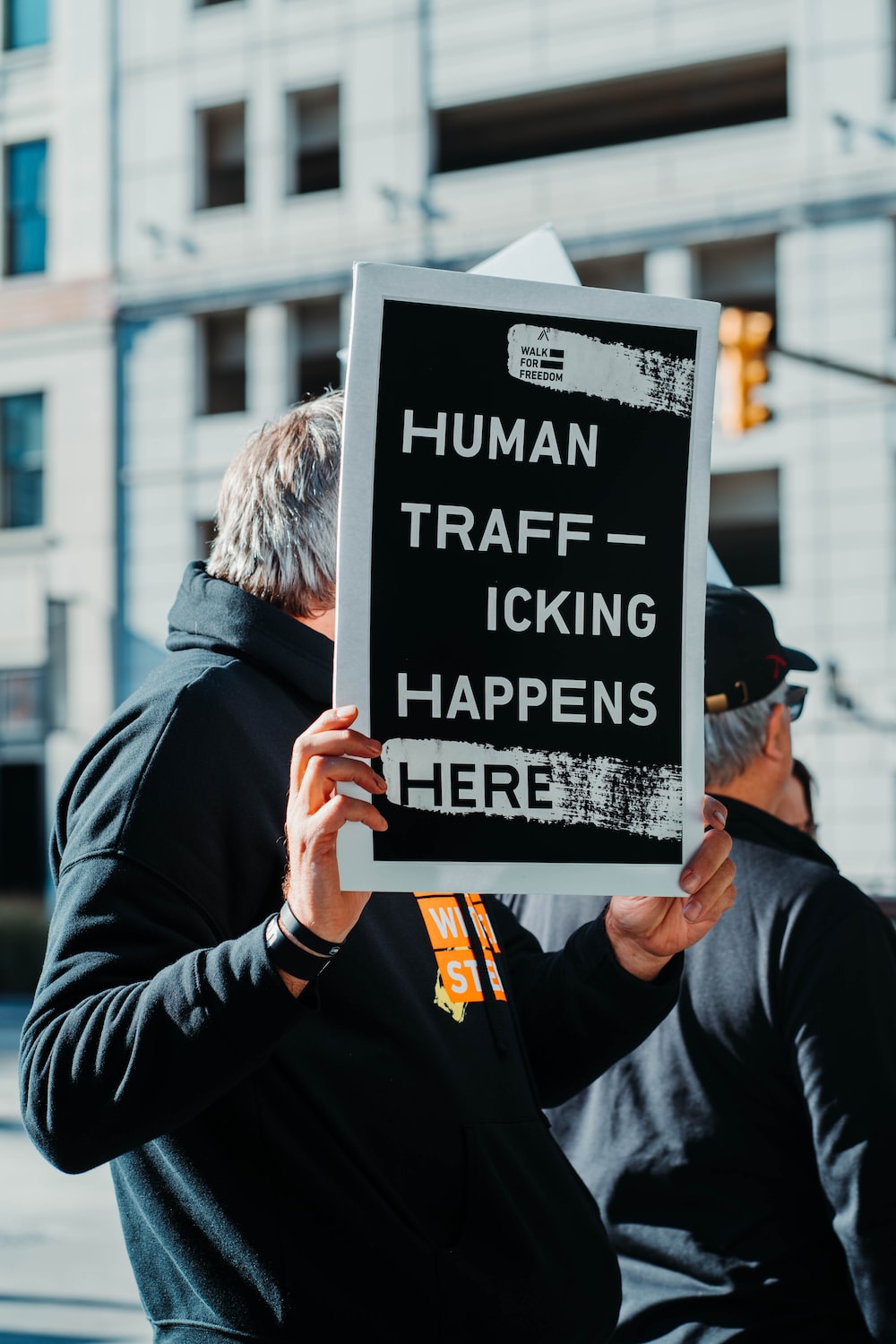 man holding sign that says human trafficking happens here