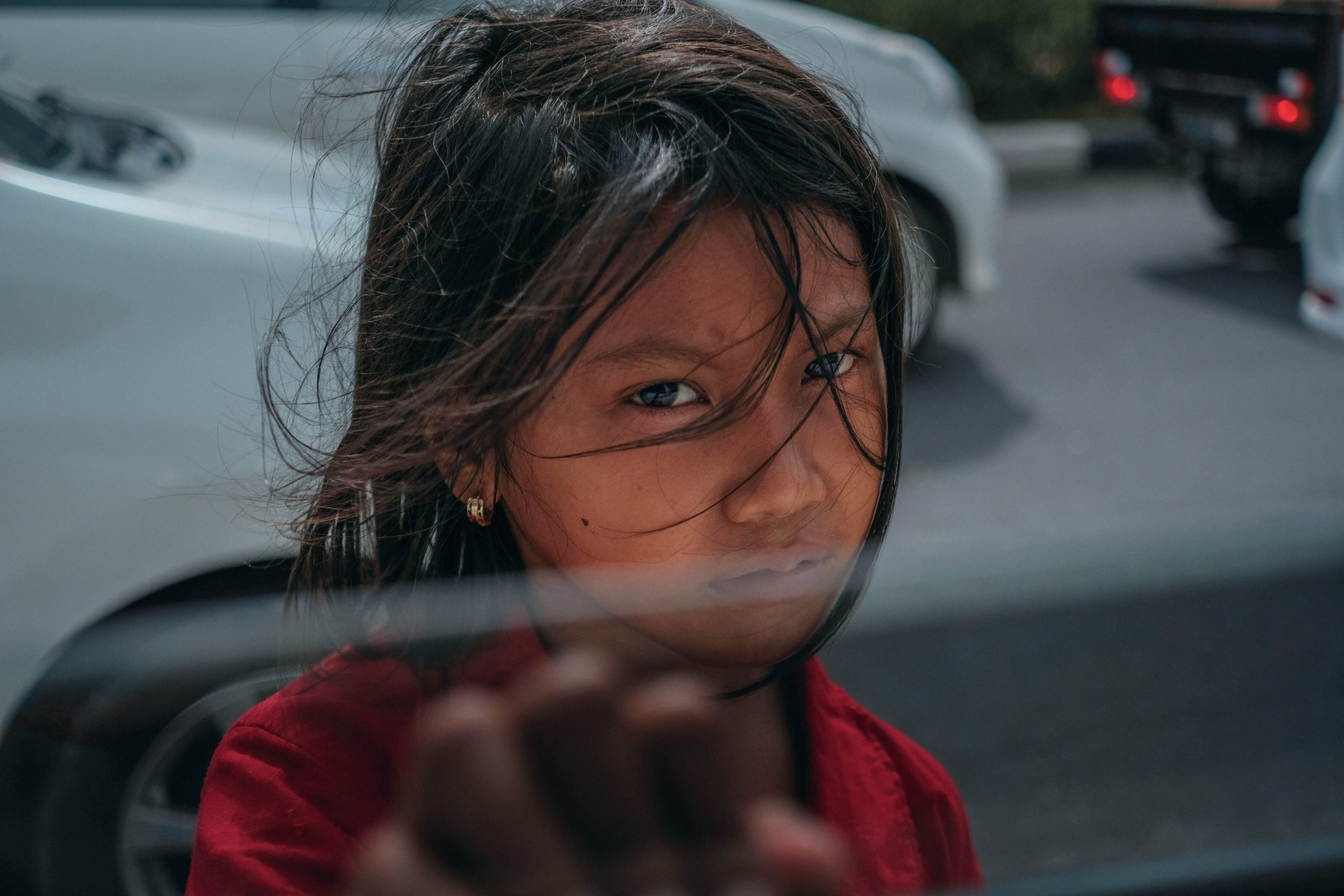 Young girl on street reaching up to car window