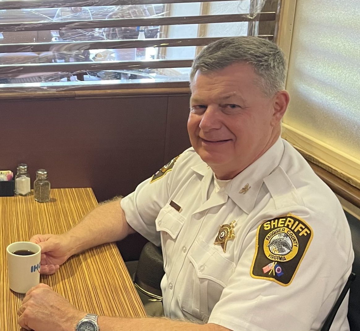 ATI Chairman of the Board, Sheriff Bob Mosier, at a restaurant table, smiling at the camera